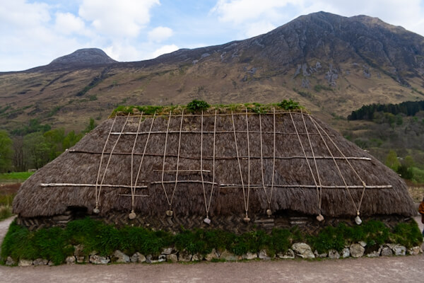 Turf House im Glencoe Visitor Centre vor majestätischen Bergen